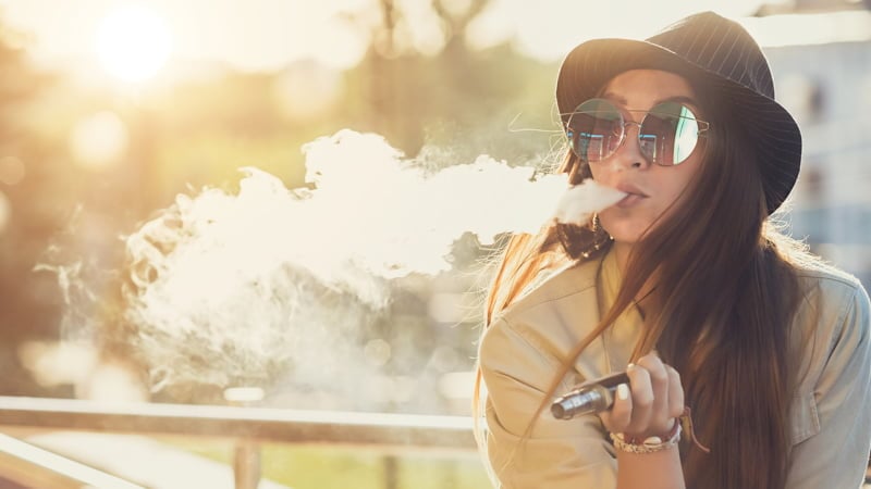 A Lady Wearing Hat Vaping Outdoor