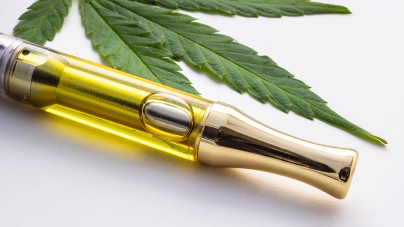 Vape Pen with THC Oil Beside a Marijuana Leaf