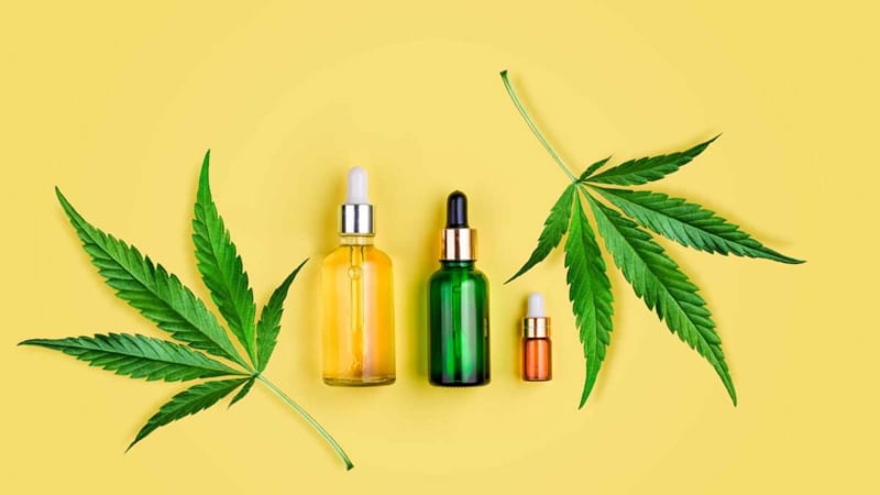 THC Oil Bottles with Marijuana Leaves in Yellow Background