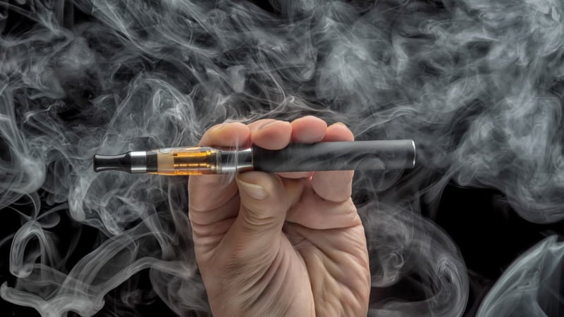 Hand Holding Vape Pen with THC Oil Surrounded by Smoke