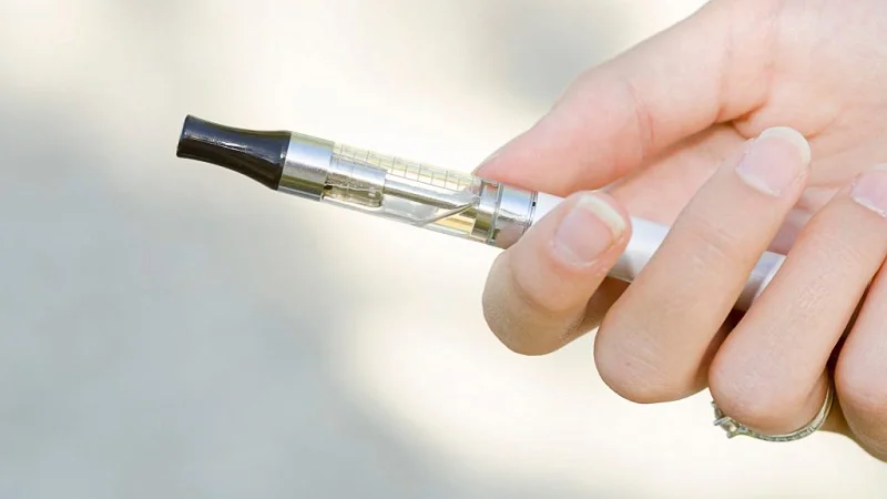 woman's hand holding a vape pen with a light background 