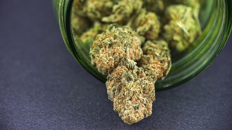 close up image of cannabis buds on green glass jar