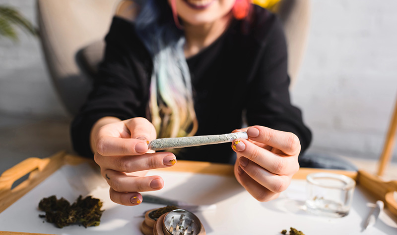 A woman holding a cannabis preroll