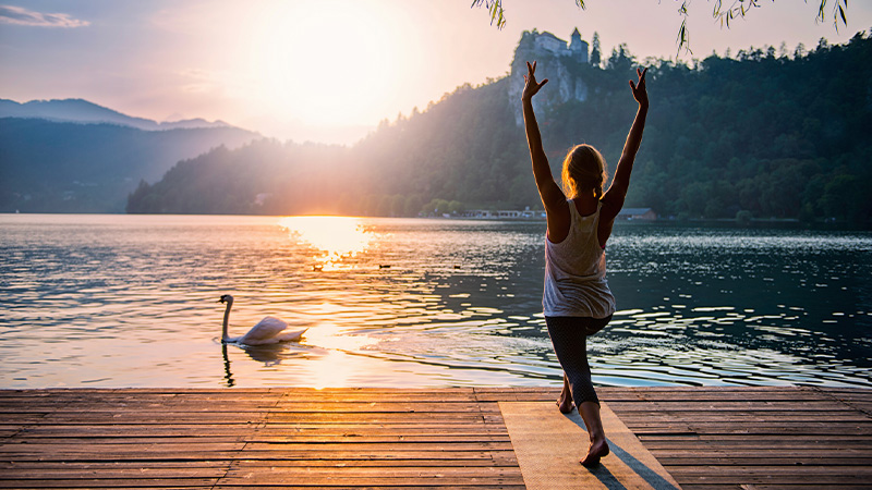 Woman doing yoga by the lake for a heathy lifestyle