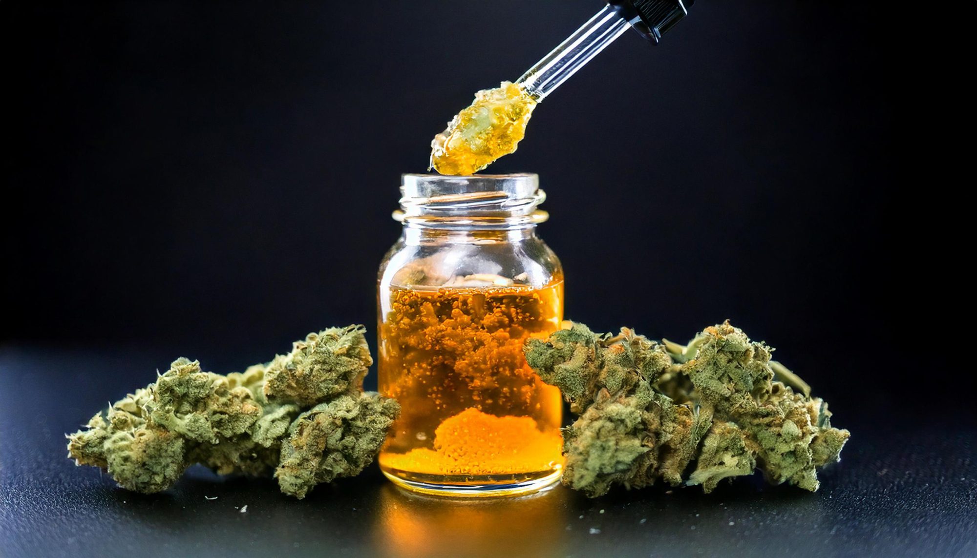 Live resin in a bottle with cannabis buds surrounding it